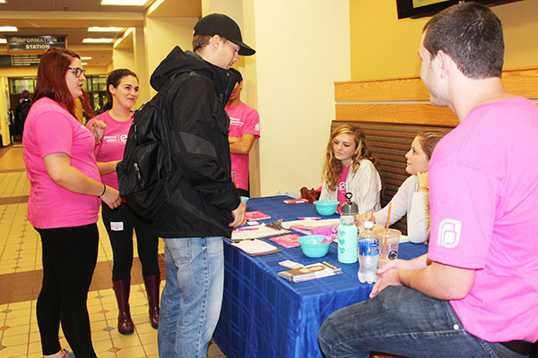 Travis Clark considers signing a petition to support Planned Parenthood. Club members from left to right, Kelsy Schorr, Tori Shriver and Jessie Savidge suround information table. 