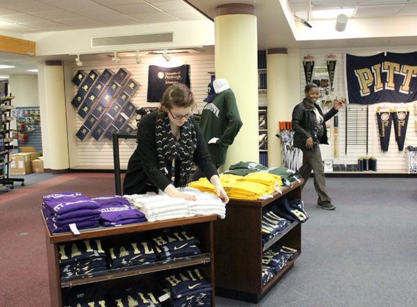 University bookstore staff member Aimee Weaber (left)  arranges apparel merchandise as co-worker Lyesha Waley walks by.