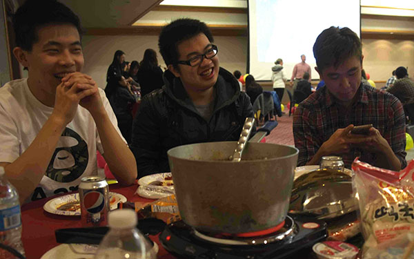 Chinese students Chen Yang, Zhu Zhuoming and Lu Zheping (left to right) are at a dining table Feb 9. at the Chinese New Year celebration in the Cambria Room. 