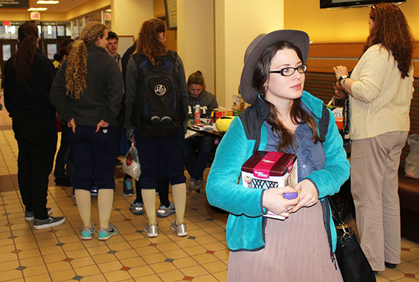 Senior Victoria Snyder holds collected eggs from the hunt and the prize she received as students collect prices in the background.