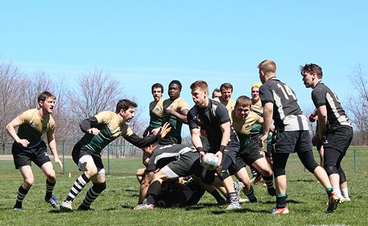 Surrounded by Point Park University rugby players are, Pitt-Johnstown’s outside center sophomore Jake Bowser runs with the ball while teammates scrum half sophomore Grady Zagorac #14 and hooker sophomore Kiel Rutters look to block for him. 