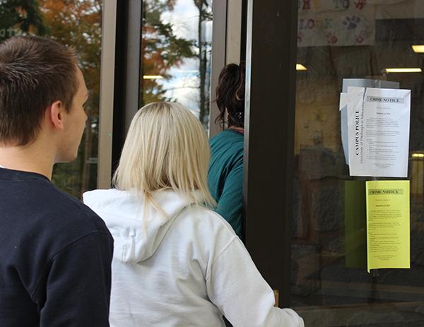 Freshmen Tyler Brown (left), Casey Atwell (middle) and Bri Fox enter Hemlock Hall where two crime notices are posted on the front door.