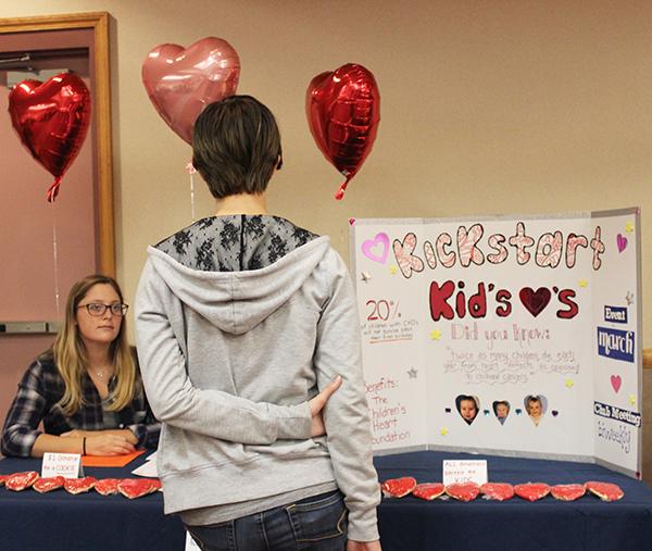 Freshman Rachel A. Heming stands in front of a Kickstart Kids’ Hearts display at an Oct 12 activities fair in Cambria Room. The club’s co-president Taylor Sultzbaugh attended the fair behind the display.