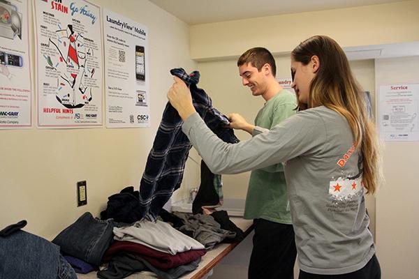 Seniors Drew Berkhoudt and Meagan Ruefle fold clothes after being notified that their laundry was done.