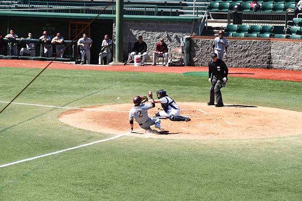 Junior catcher Nico Pecora is about to receive the ball to tag out a player from Gannon University sliding into home plate.
