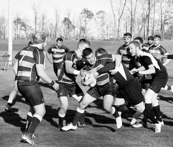 Junior outside center Jared Hoover fights his way through Thiel players to score in Saturday’s match.