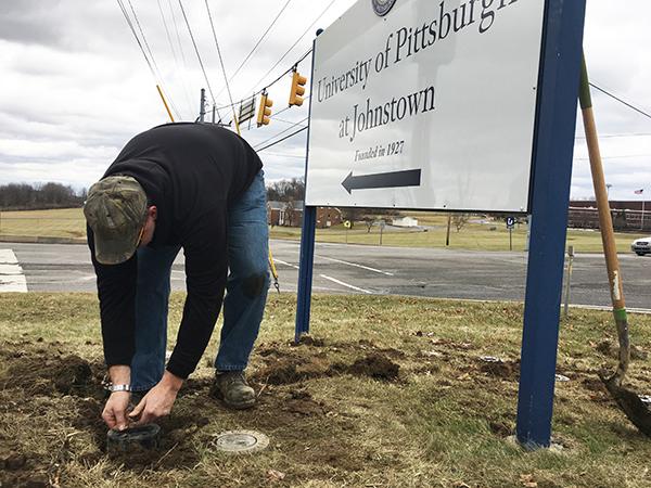 Tom Helsel sets up lighting at the base of a university sign in front of the College Park Apartments Jan. 12.