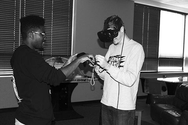 Senior Demar Watson helps freshman Allen Griffith learn how to use a virtual reality equipment in the Zone