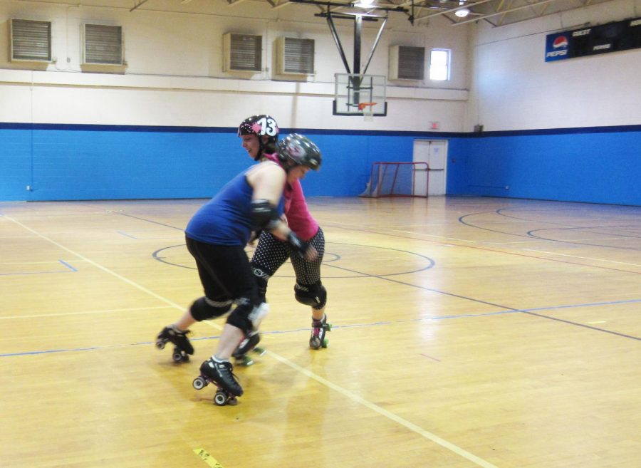 Johnstown Roller Girls team members Barb Mitchell and Kayla Blough, both of Johnstown, demonstrate what it looks like to hit an opponent in a game.