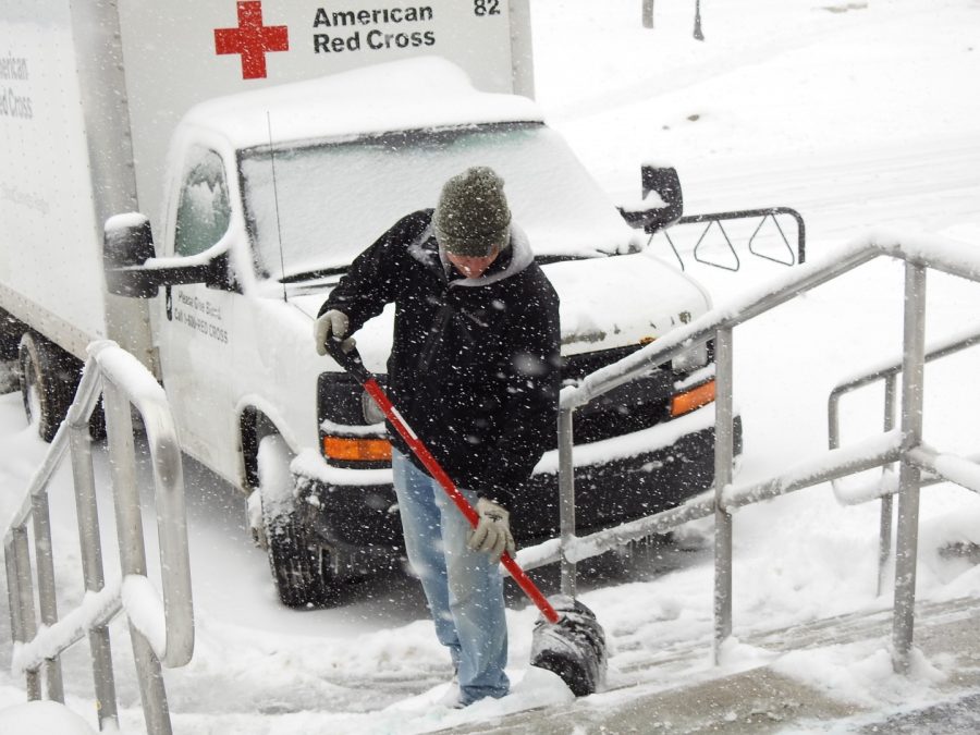 Physical Plant employee Taylor Slagle shovels snow March 21 from the steps near a Student Union entrance.