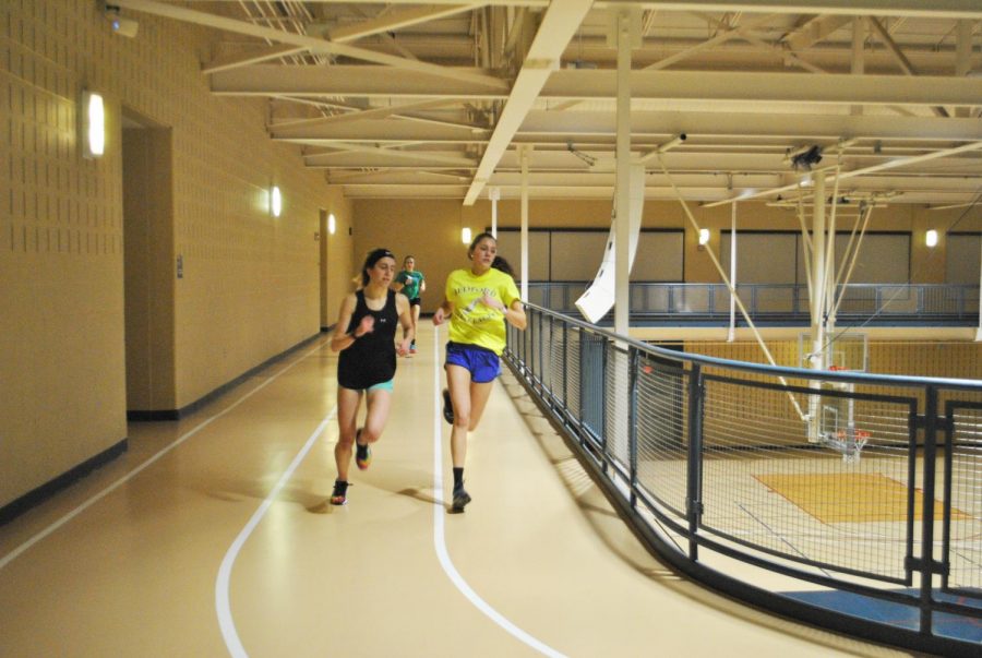 The women’s track and field team trains Jan. 16 in the Wellness Center, running laps around the track above the gym.