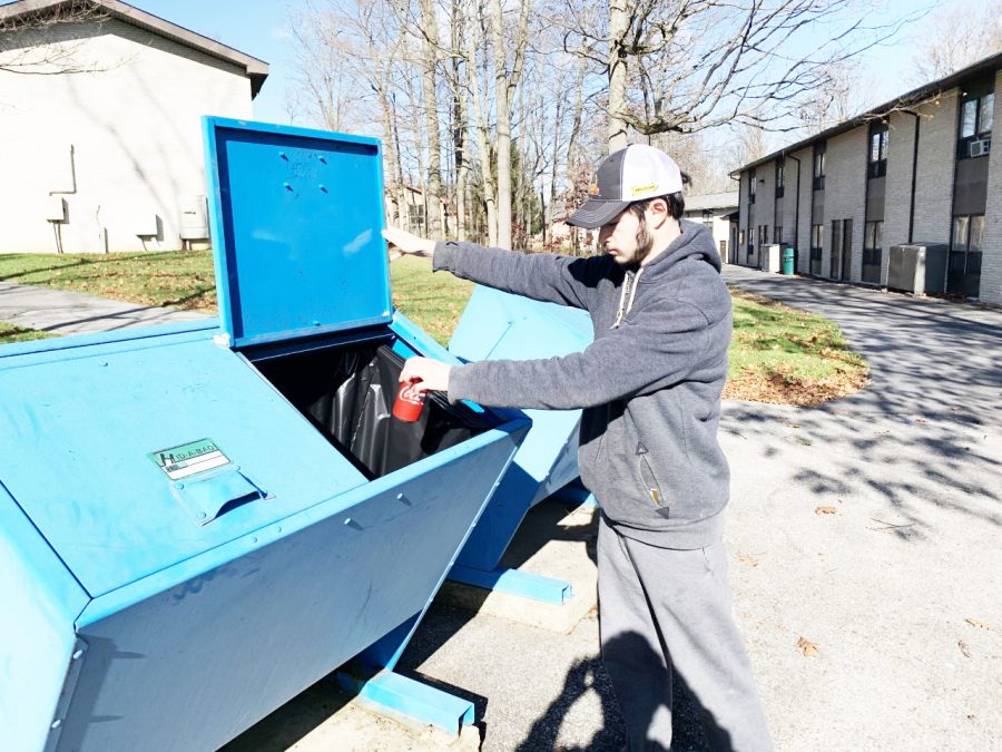 Junior Brennan Brokaw recycles in the pale blue bins near the Summit townhouse Sunday. Brokaw said that this was his first time using the bins, because he thought that the bins were mailing bins as opposed to recycling bins. 